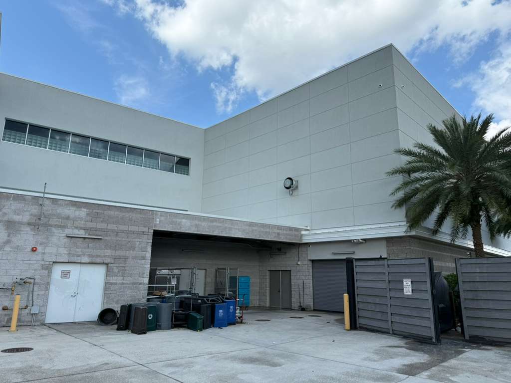 commercial-building-exterior-with-waste-containers-and-palm-trees