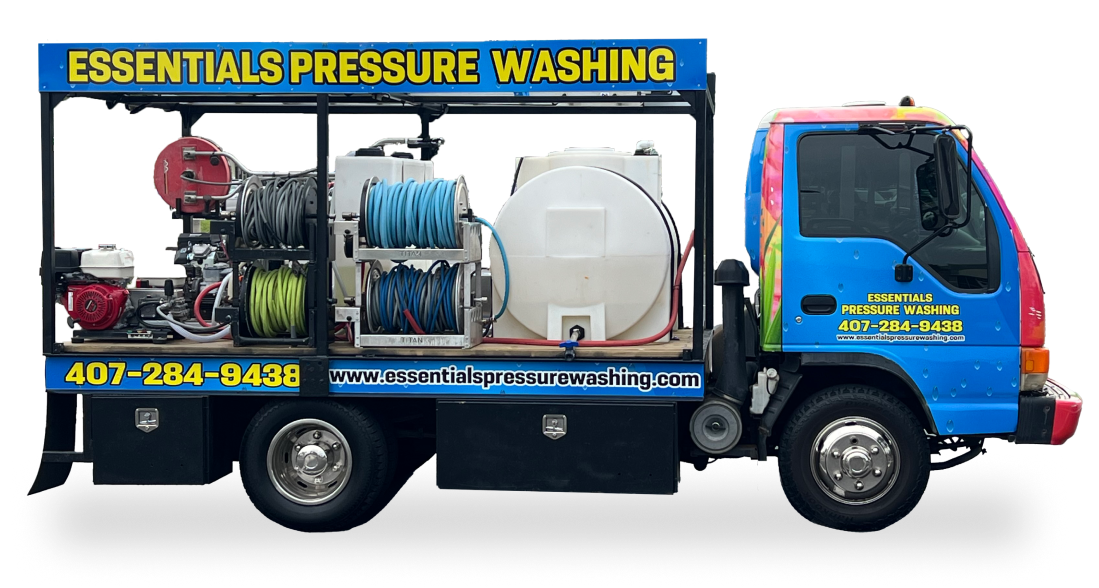 A branded Essentials Pressure Washing truck equipped with pressure washing equipment, water tanks, and hoses, displaying the company’s contact information and website.